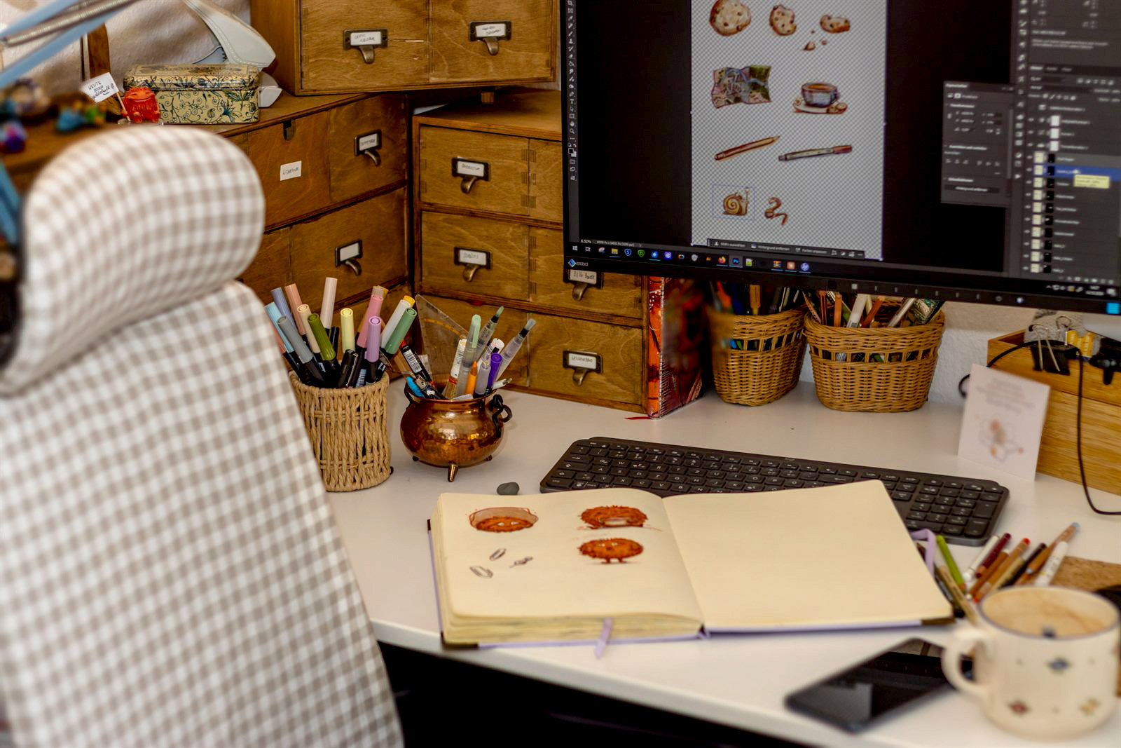 Arbeitsplatz mit Karo-Stuhl, Skizzenbuch und Monitor